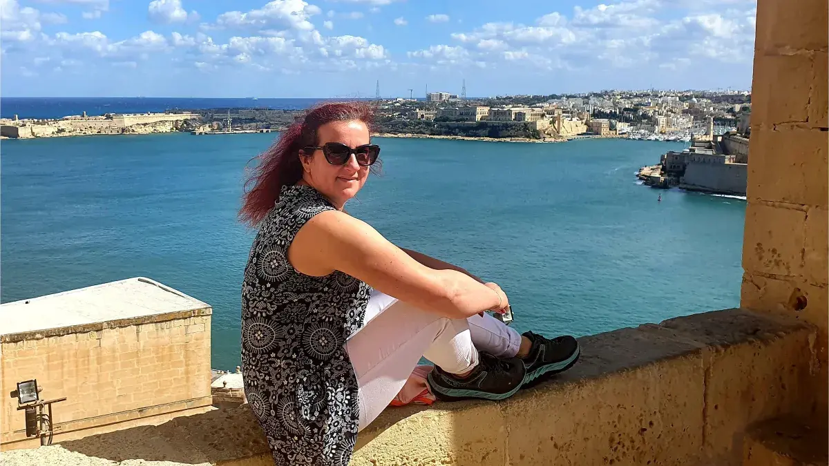 Romana Gorjanc sitting on a wall by the sea