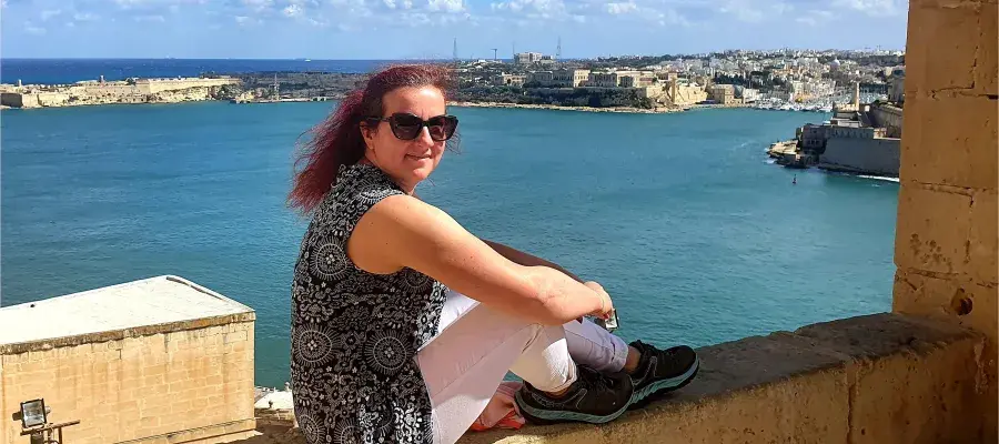 Romana Gorjanc sitting on a wall by the sea