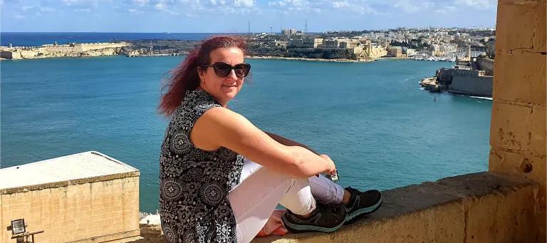Romana Gorjanc sitting on a wall by the sea