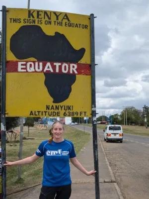 Amy under a sign showing that this is as the equator